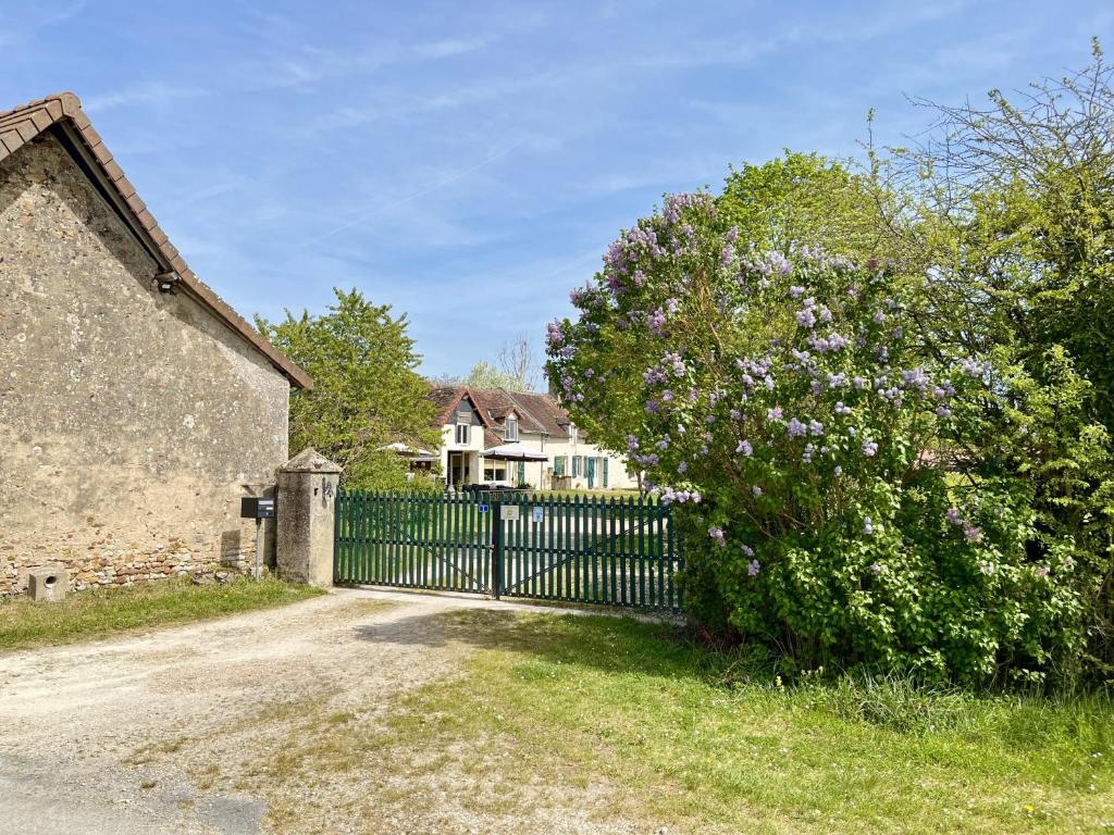 a fence in front of a house with a flowering bush at Voilà Le Logat - Chambres & Gîtes in Sainte-Gemme