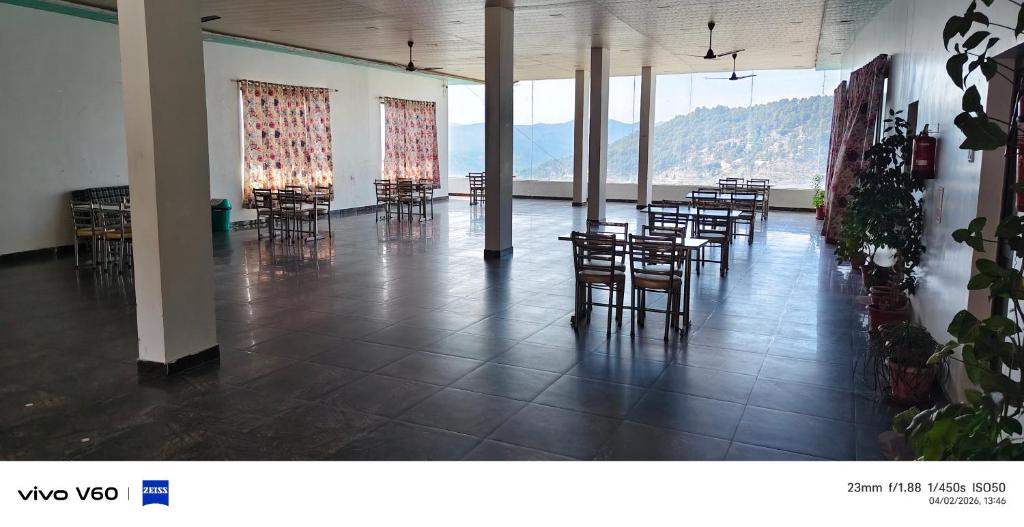 a room with tables and chairs with mountains in the background at Hotel Ratnouday in Kāndi