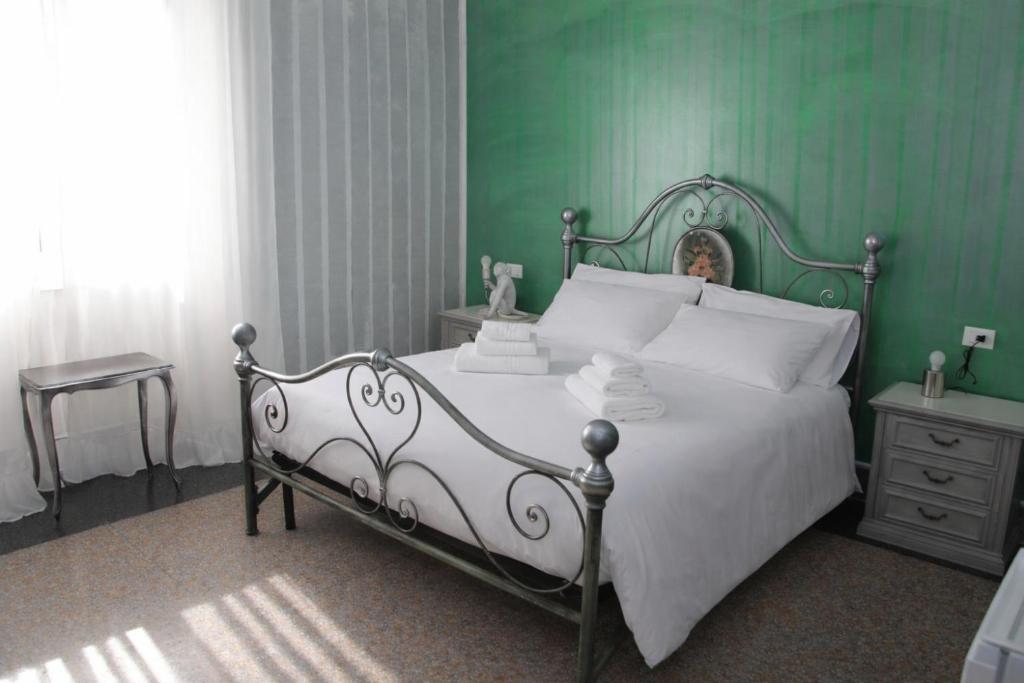 a bedroom with a white bed with a green wall at The Corner Tivoli in Tivoli