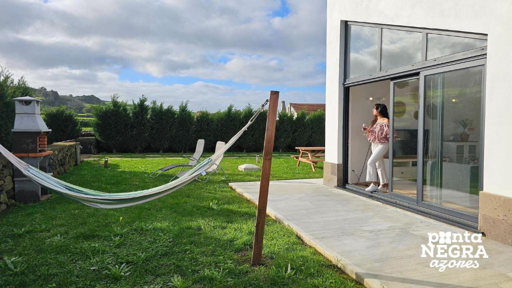 a woman standing outside of a house with a hammock at Bird House by PontaNegraAzores in Altares