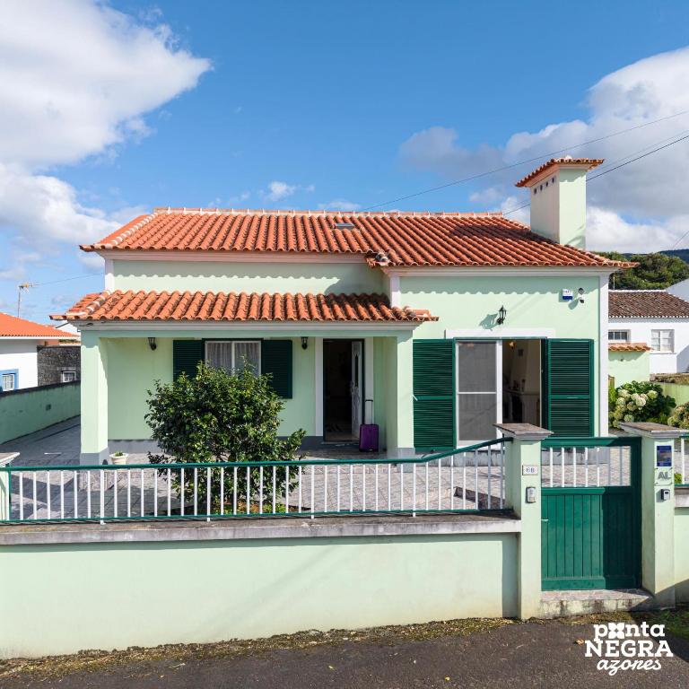 a white house with green shutters and a balcony at Casa Martins by PontaNegraAzores in Biscoitos