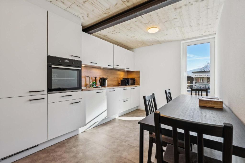 a kitchen with white cabinets and a table with chairs at FENUS SGT01 moderne Ferienwohnung in Grabs