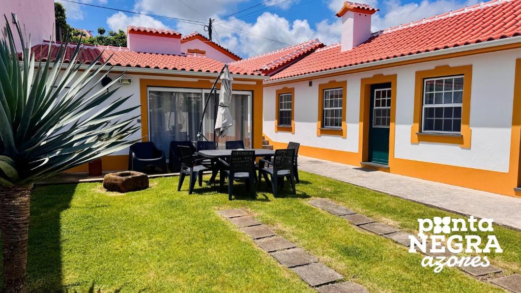 a patio with a table and chairs in front of a house at Alojamento Ponta Negra in Biscoitos