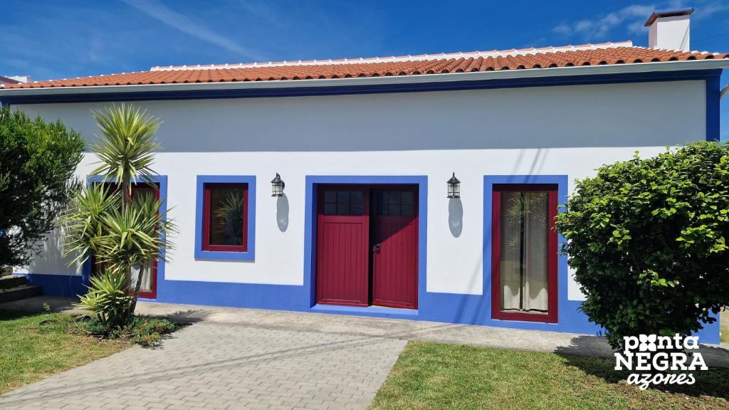 a blue and white house with red doors at The North House by Ponta Negra Azores in Biscoitos