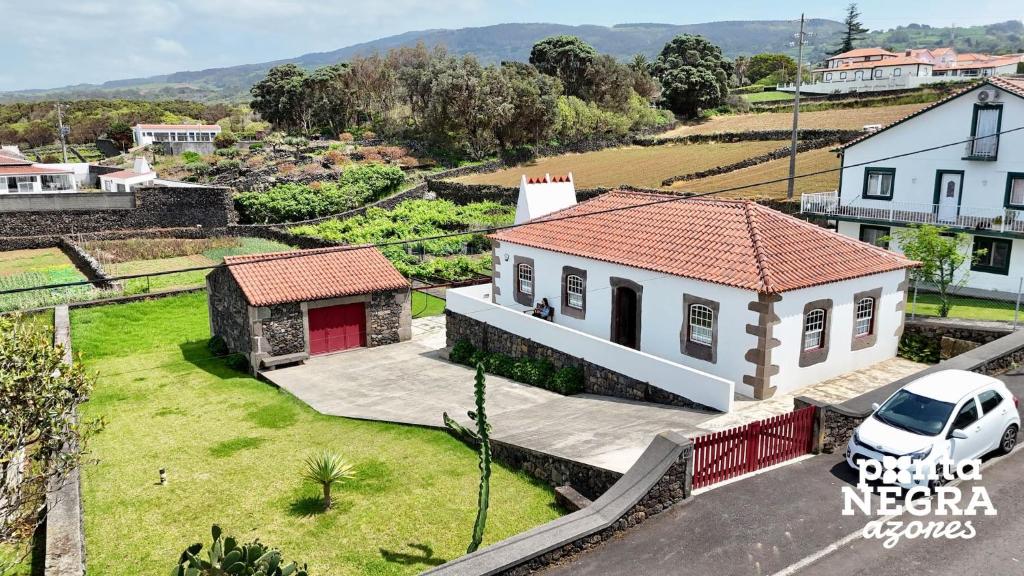 a white house with a car parked in front of it at Casa da Hortênsia Roxa by Ponta Negra Azores in Praia da Vitória