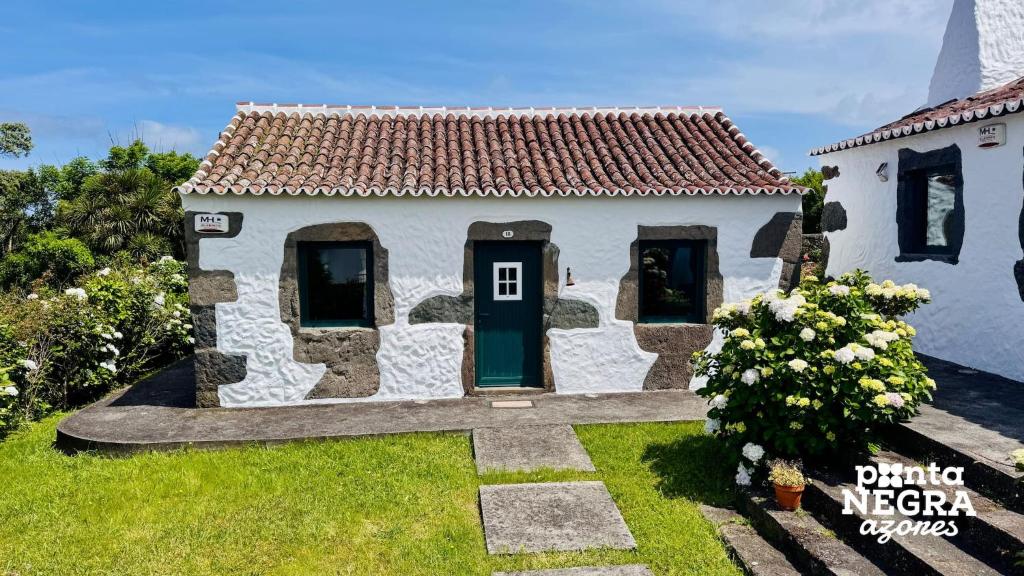 a small white house with a green door at Casa da Serreta by PontaNegraAzores in Serreta