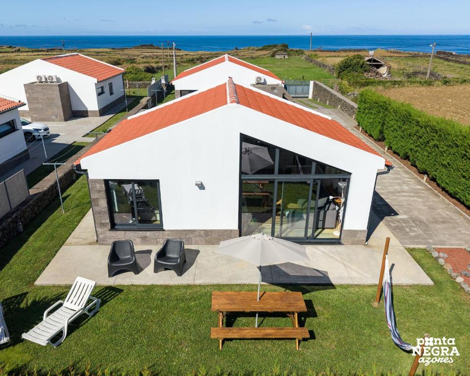 a house with a table and chairs and an umbrella at Wine House by Ponta Negra Azores in Altares