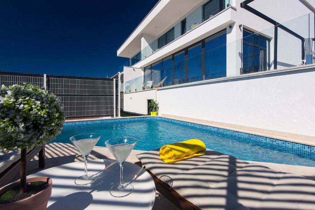 a swimming pool with a table and glasses next to a house at Villa Benić in Crikvenica