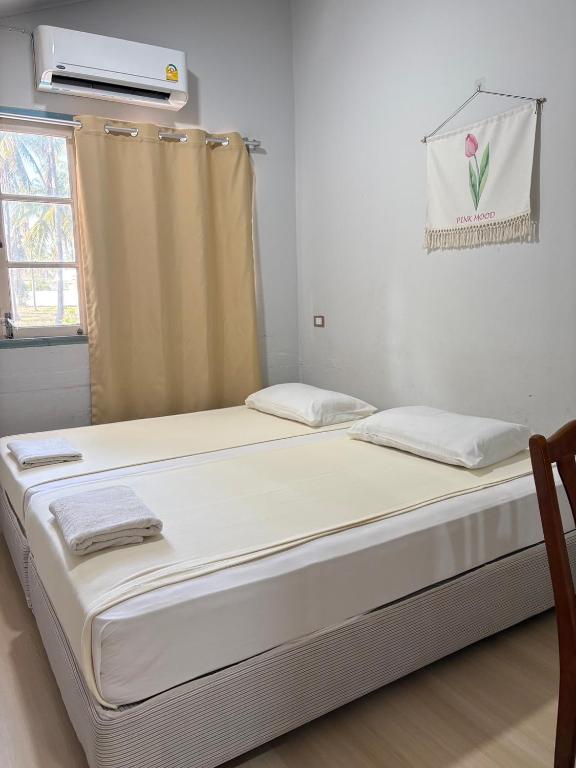two beds in a room with a window at Tharnvara Resort in Ban Khok Sung