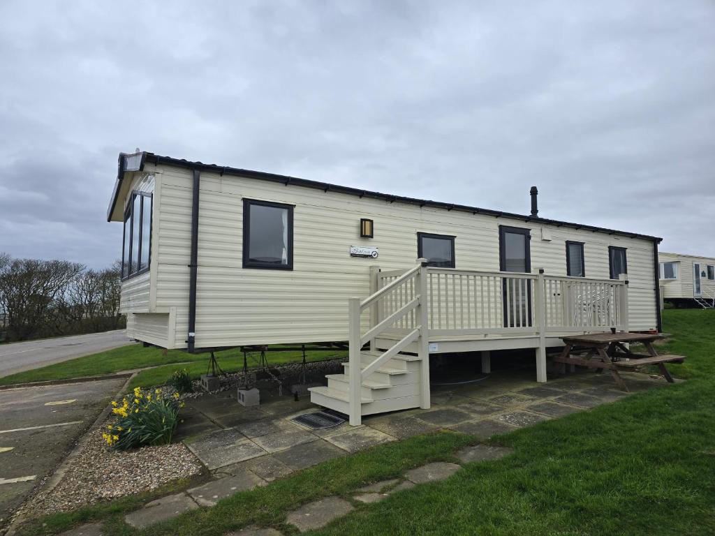a mobile home with a porch and a deck at Seaside Caravan Home in Reighton