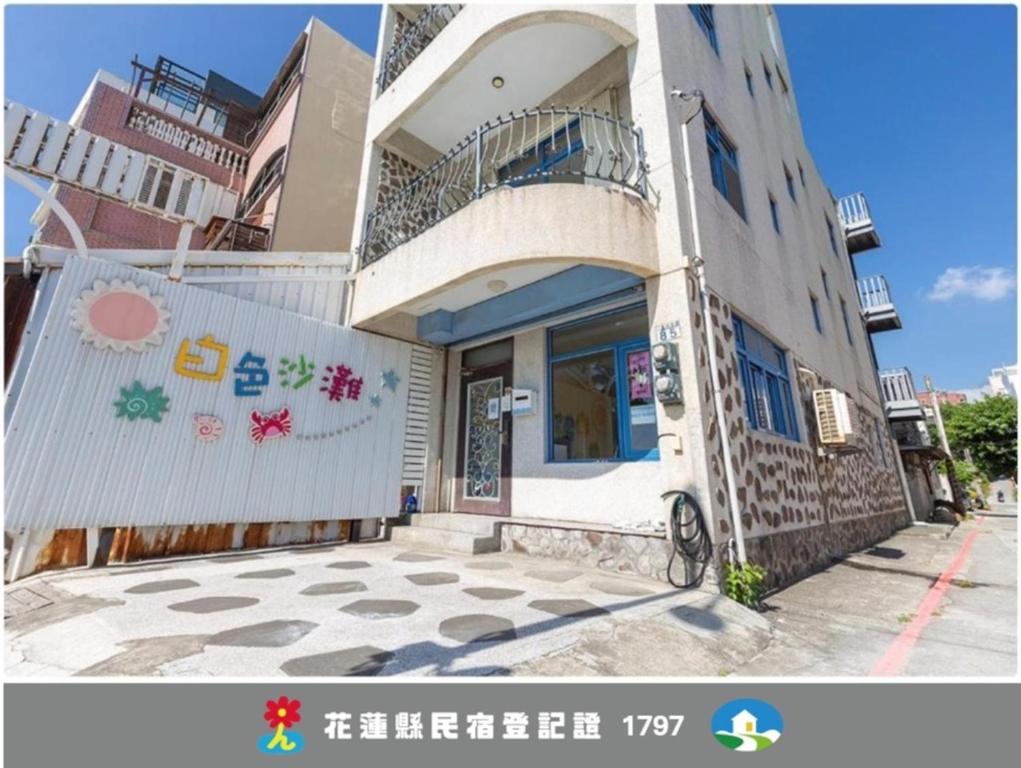 a white building with a balcony on top of it at White Sand Homestay in Hualien City