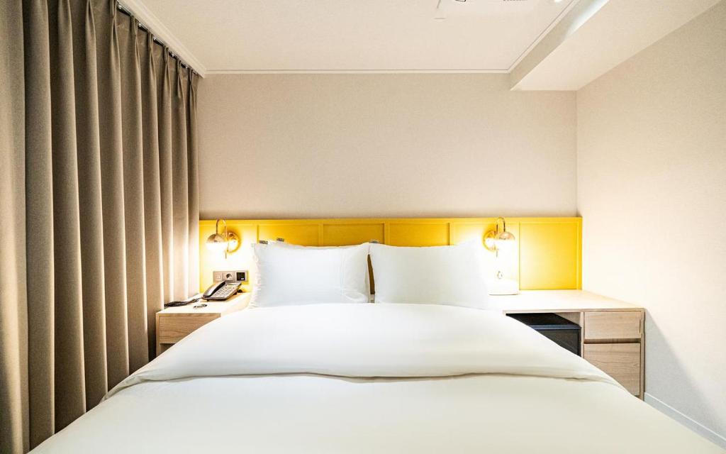 a bedroom with a large white bed and two lamps at 신촌 APL Hotel in Seoul