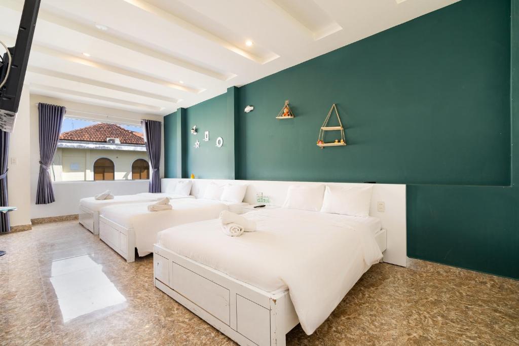 a room with two beds and a green wall at Gia Khanh Hotel in Da Lat