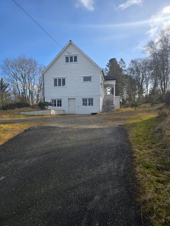 a white barn on a road next to a field at Cabin in Leirvåg in Leirvåg