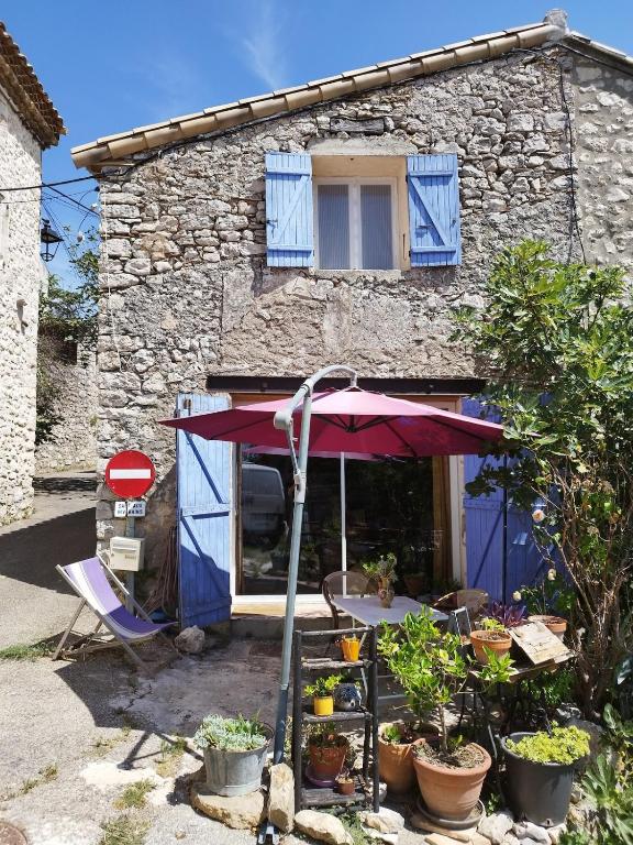 a house with a table and an umbrella in front of it at à 10 mn des Gorges de l'Ardèche in Bidon