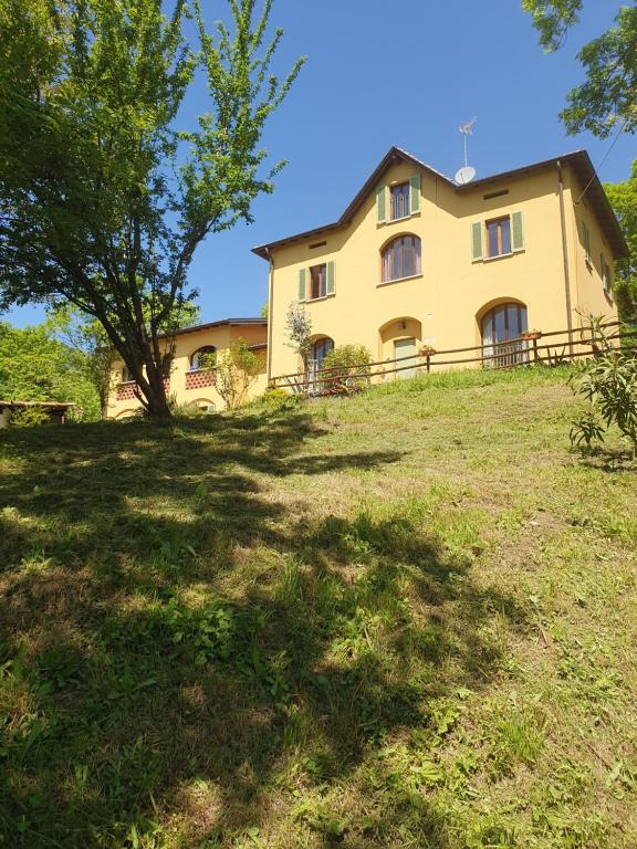 a large yellow house on a hill with a tree at Casa Vacanza Cascina Ronco relax nella natura vicino a Como e Bellagio in Erba