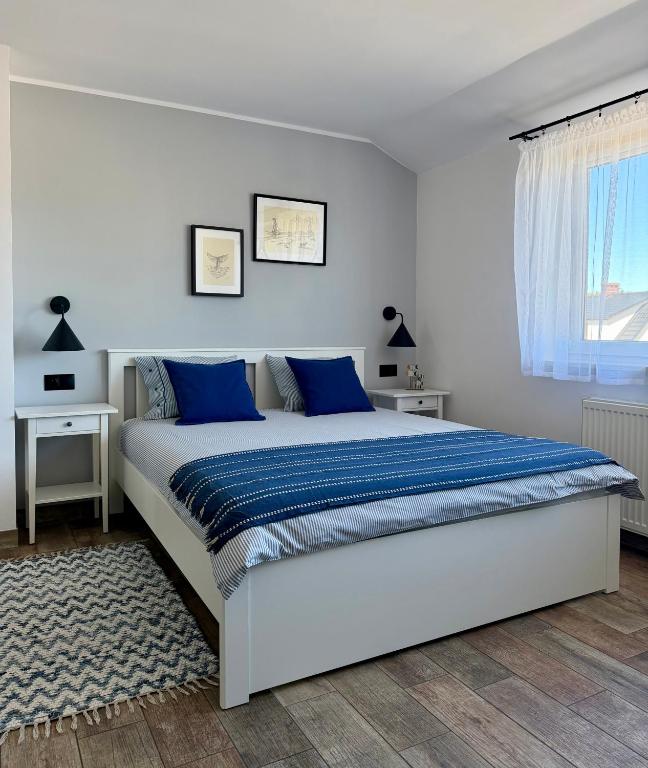 a white bedroom with a large bed with blue pillows at Morza Szum in Dziwnów