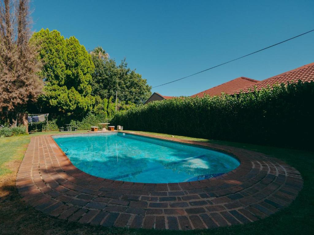 a swimming pool in a yard with a brick patio at Cosy - Best Rest Potch in Potchefstroom