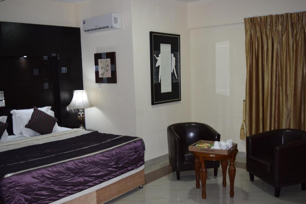 a bedroom with a bed and a chair and a table at Citiheight Hotel in Ikeja