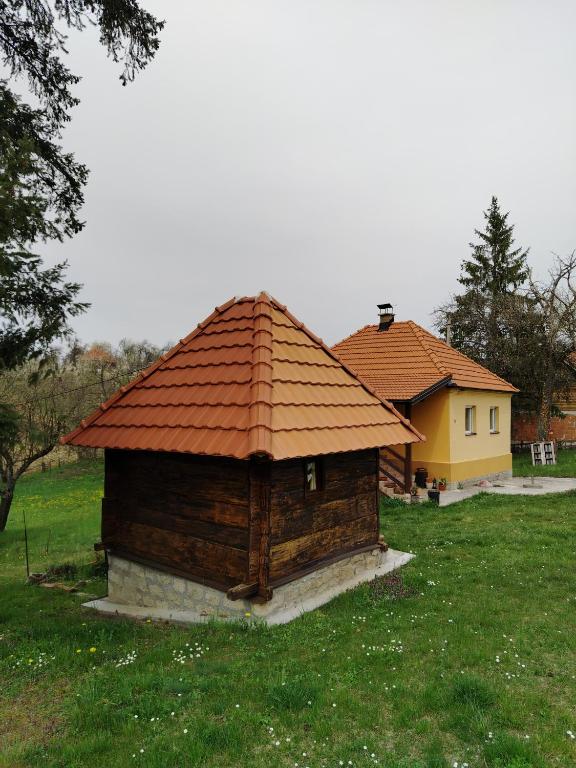 a small building with a red roof in a field at Seosko domacinstvo Gardic in Užice