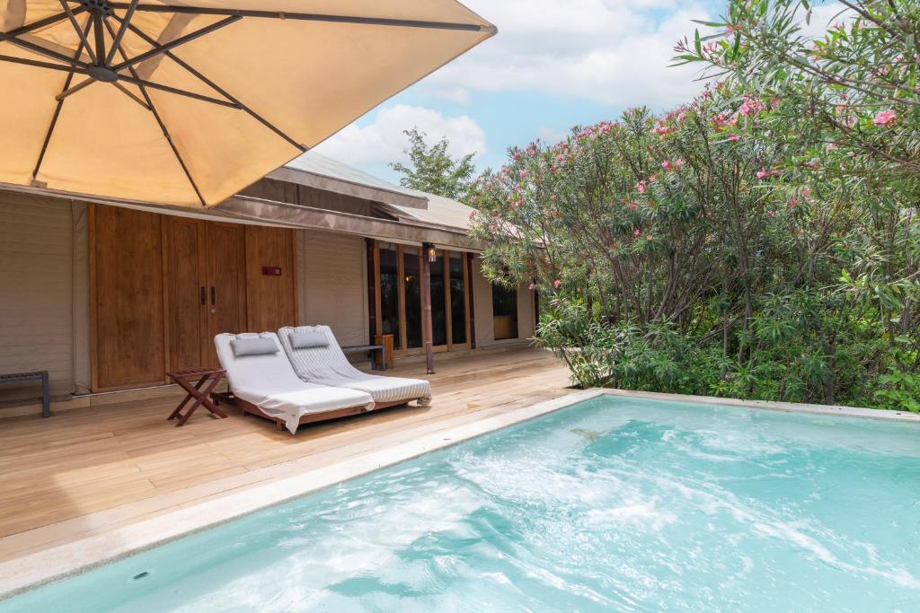 a pool with a chair and an umbrella next to a house at The Vineyard Hideaway Khaoyai in Ban Wang Phaem
