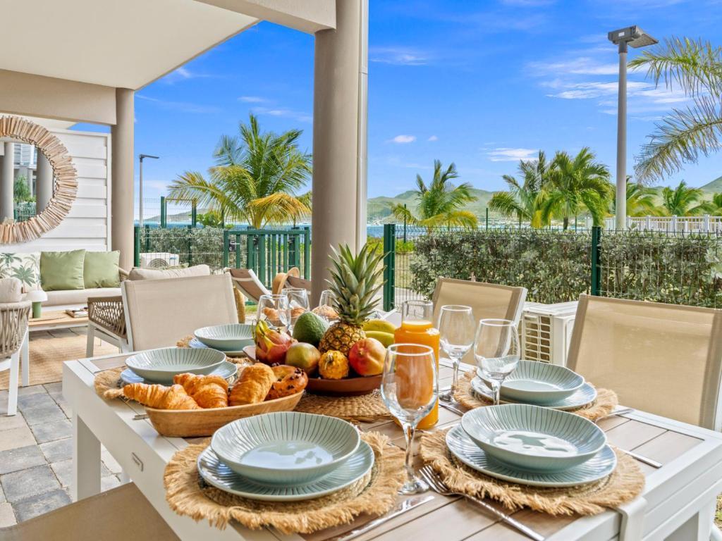 a table with food and wine on a patio with palm trees at Ocean Breeze, Fully Renovated Beachfront 2 bdr in Baie Nettle