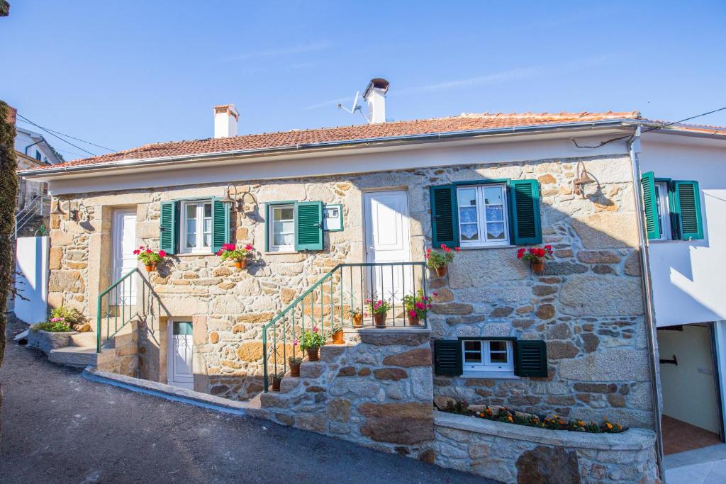 une maison en pierre avec des fenêtres et des escaliers verts dotés de volets. dans l'établissement Cabanelas Country House - Casa do Afonso, à Vale de Cambra