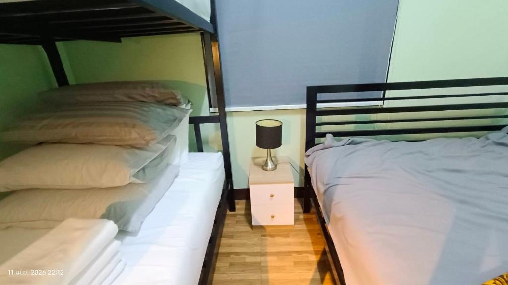 a bedroom with two beds and a lamp on a night stand at Chic Homestay Narathiwat in Ban Kam Pong Ba Ru