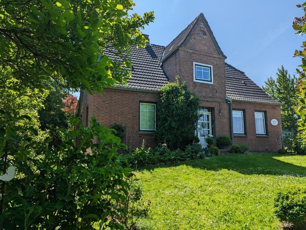 an old brick house with a grass yard at Ferienhaus Swanen Hus in Nordstrand