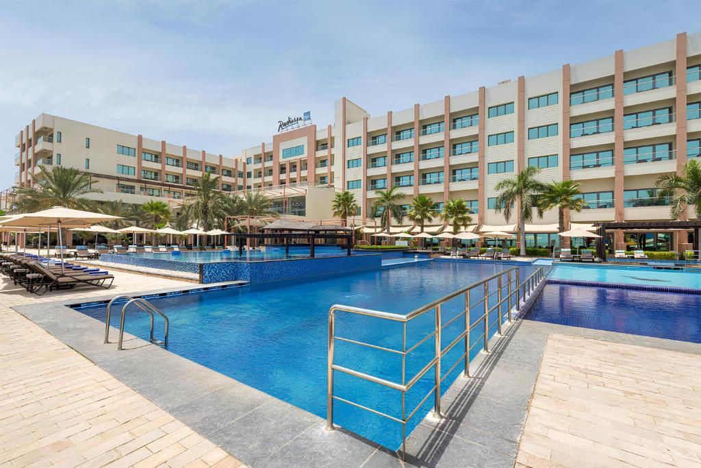 a large swimming pool in front of a hotel at Radisson Blu Hotel & Resort, Sohar in Sohar