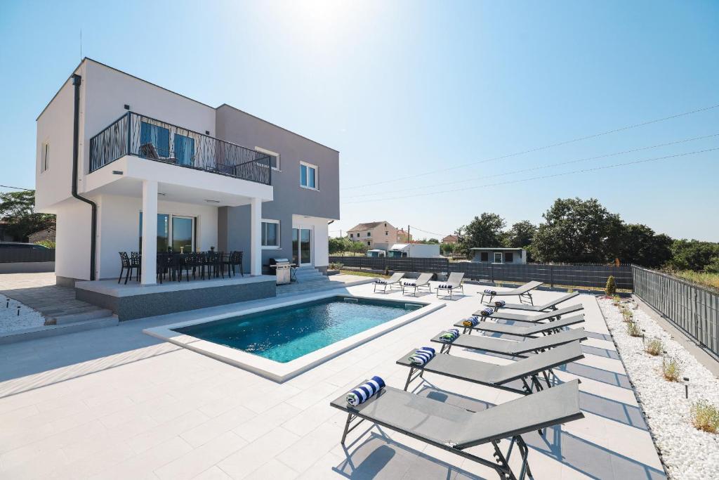a villa with a swimming pool and lounge chairs at Villa IviCasa with pool in Murvica