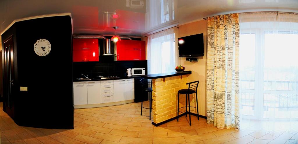 a kitchen with red cabinets and a black counter at Студия и отдельная спальня в Центре in Mykolaiv