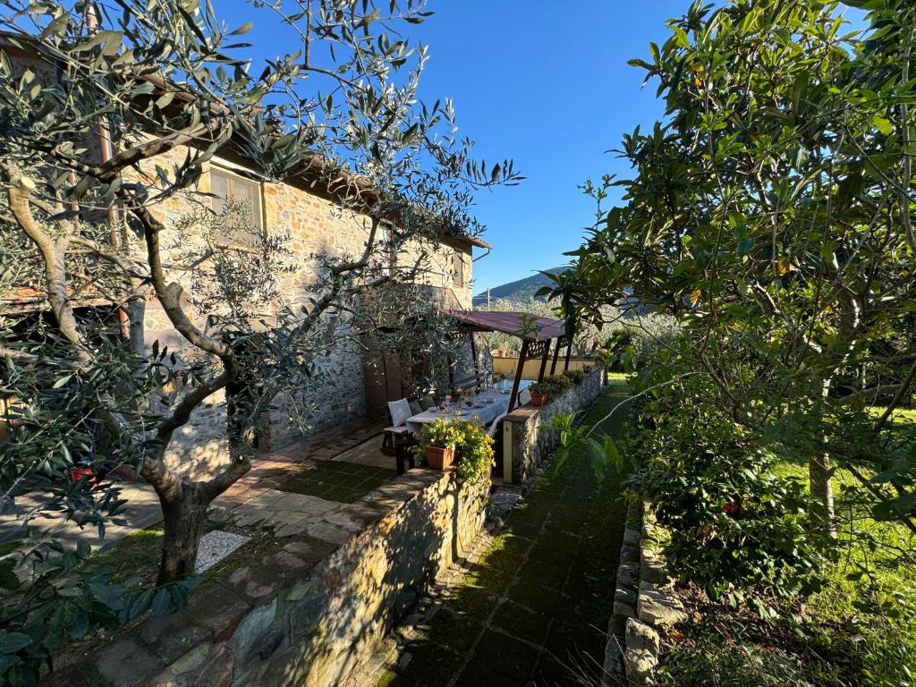 a stone house with a garden and trees at Podere di Mero Casolare in Buti