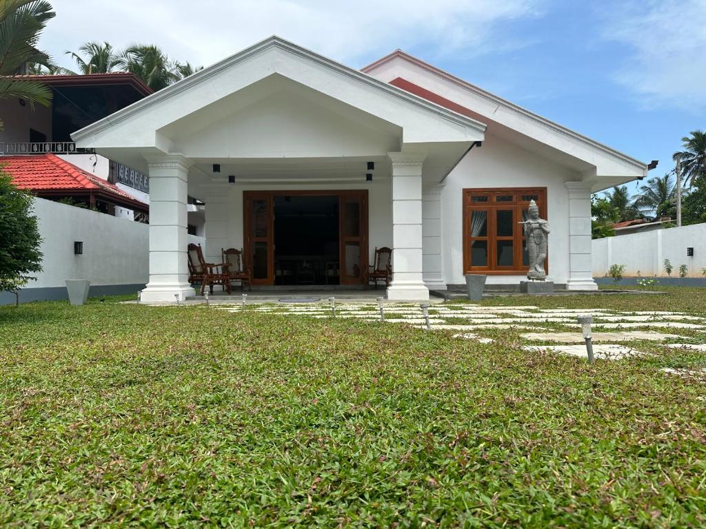 a white house with a lawn in front of it at SAHAS Villa - Private Riverfront Garden Retreat in Beruwala in Beruwala
