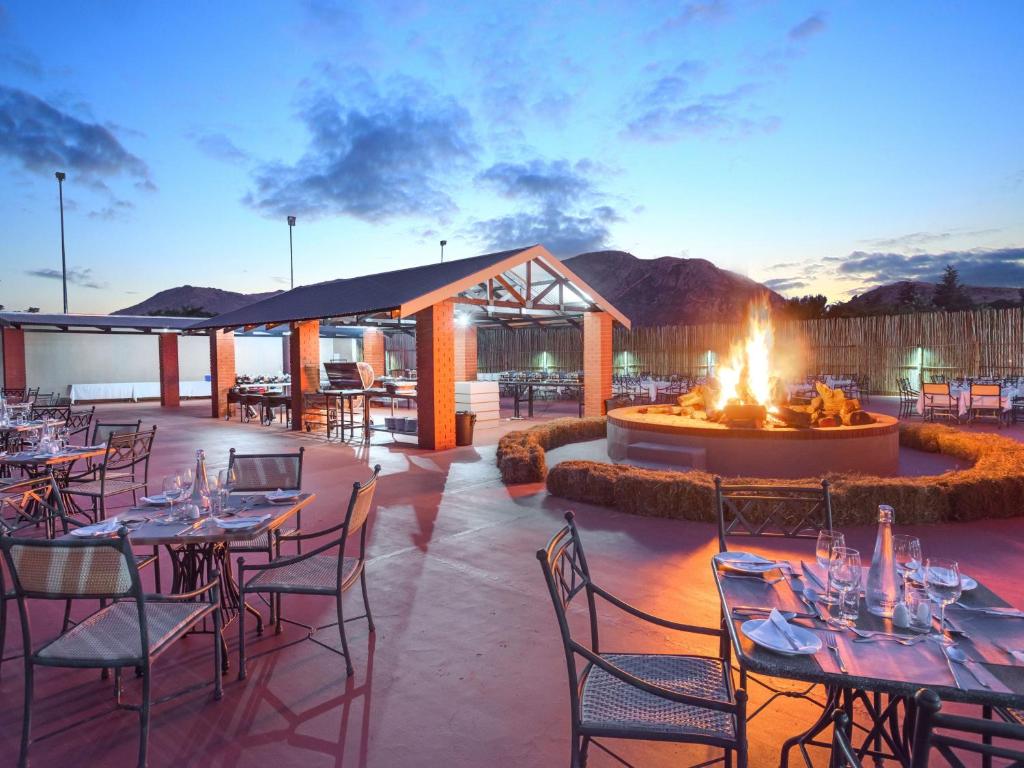 a restaurant with tables and chairs and a fire pit at ANEW Resort Hunters Rest Rustenburg in Rustenburg