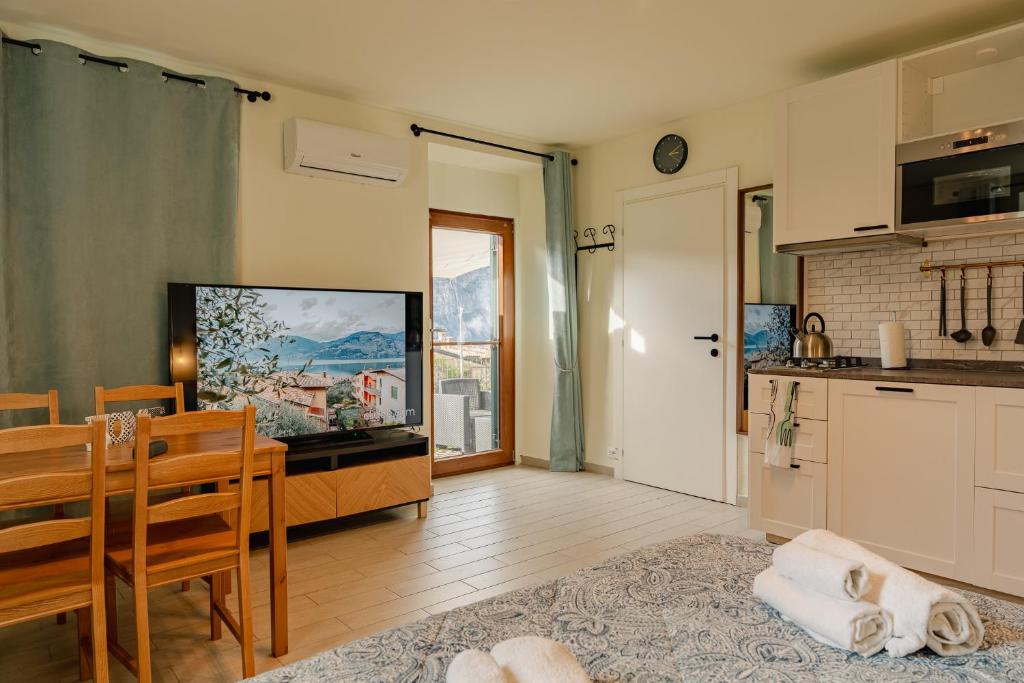 a kitchen and dining room with a table and a television at Casa Galya with private patio by GardaDoma in Brenzone sul Garda