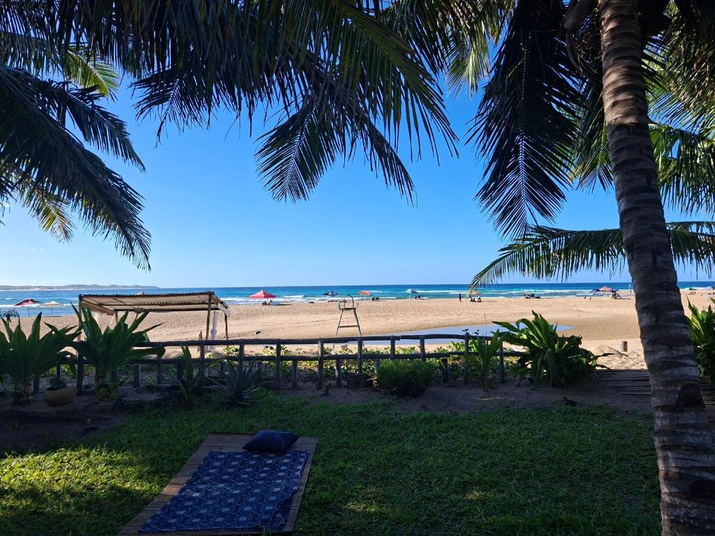 a view of a beach with a swing and palm trees at Dhow Blue * Tofo Beach in Praia do Tofo