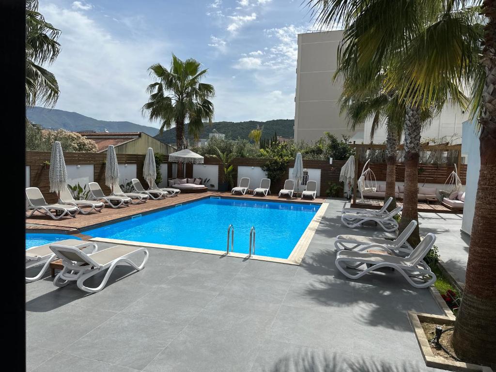 a swimming pool with chaise lounges and chairs around it at Kuburi Hotel in Ksamil