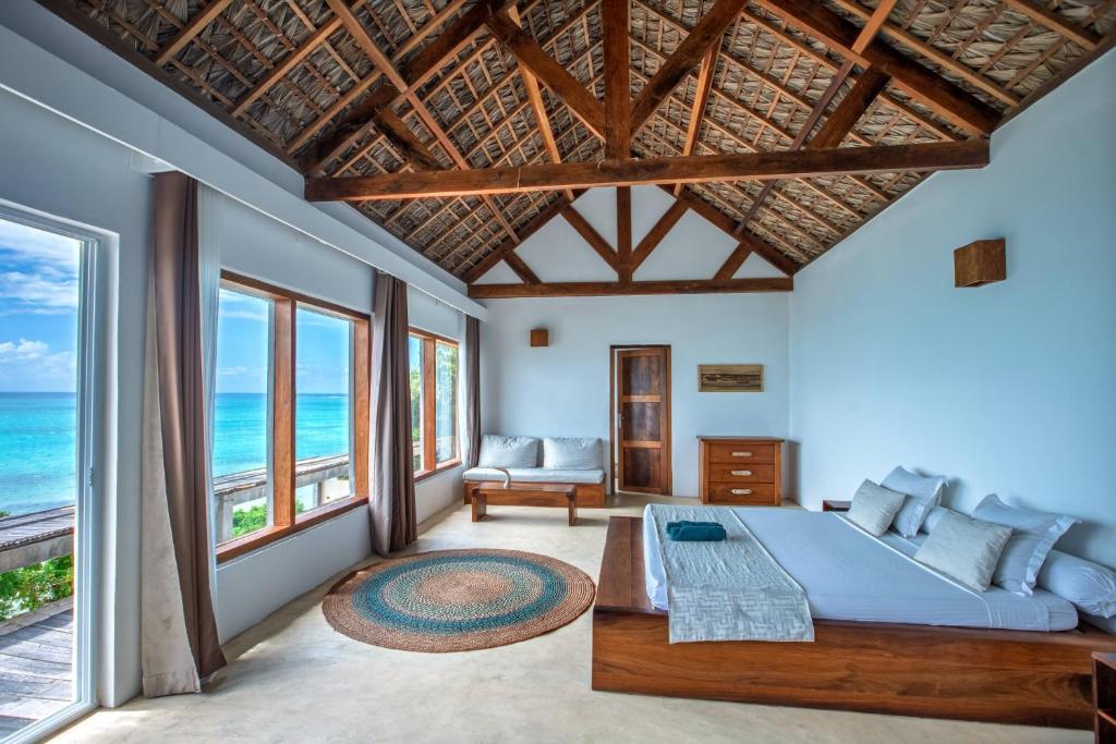 a bedroom with a large bed and large windows at Mazava Loha Resort in Antsiranana