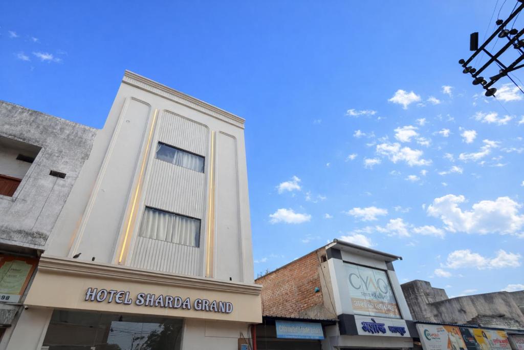 a tall white building with a window on a street at Sharda Grand in Ujjain