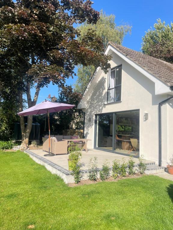 a house with a table and an umbrella in the yard at Rhubarb Cottage in Navan