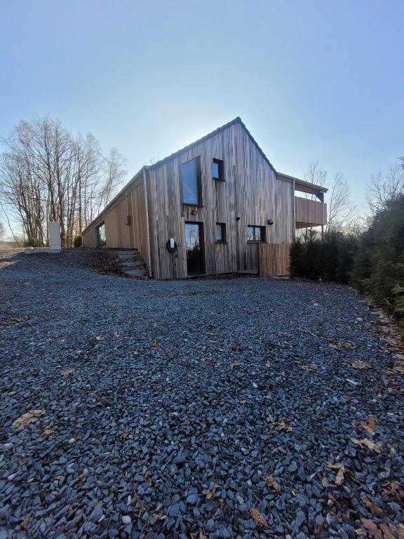 a barn on a gravel road in front of a building at Gîte DDS - Bridge into nature! in Manhay
