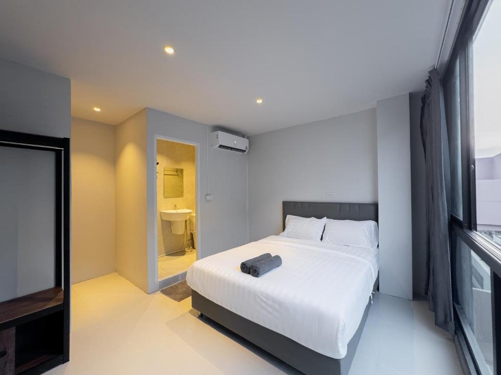 a bedroom with a white bed and a television at On The Six Studios Pratamnak in Pattaya South
