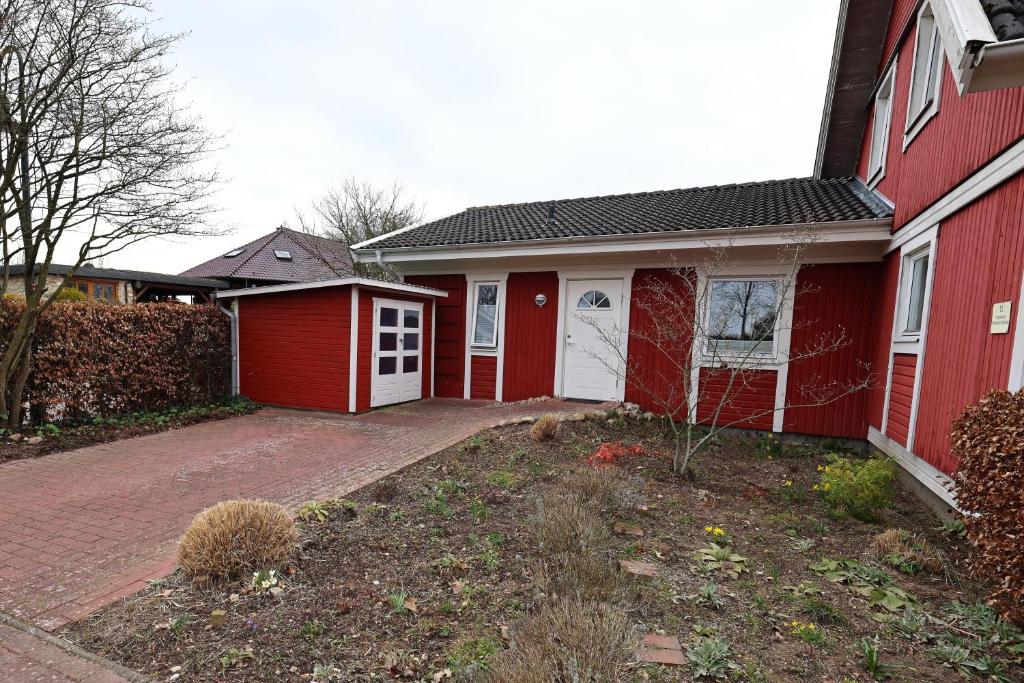 a red house with a garage and a driveway at Schwedenhaus Westensee 1 EG in Groß Vollstedt