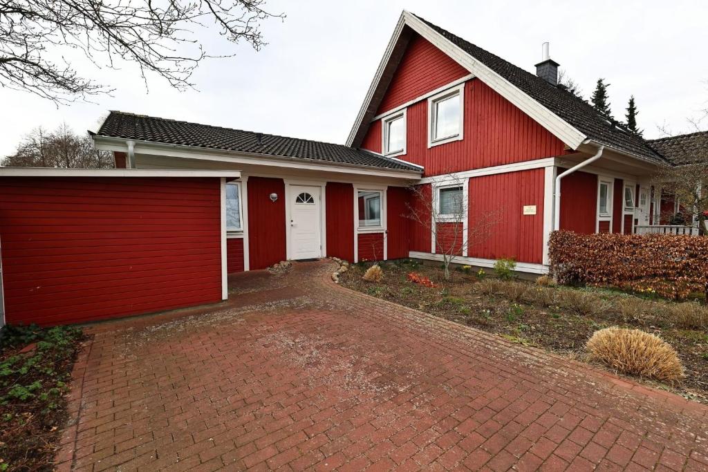 a red house with a red garage at Schwedenhaus Westensee 2 OG in Groß Vollstedt