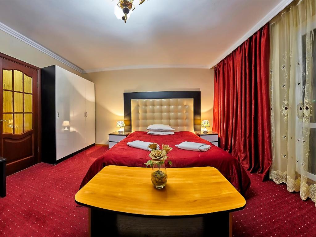 - une chambre avec un lit rouge et une table en bois dans l'établissement Sanatorium Elite Dnipro, à Trouskavets