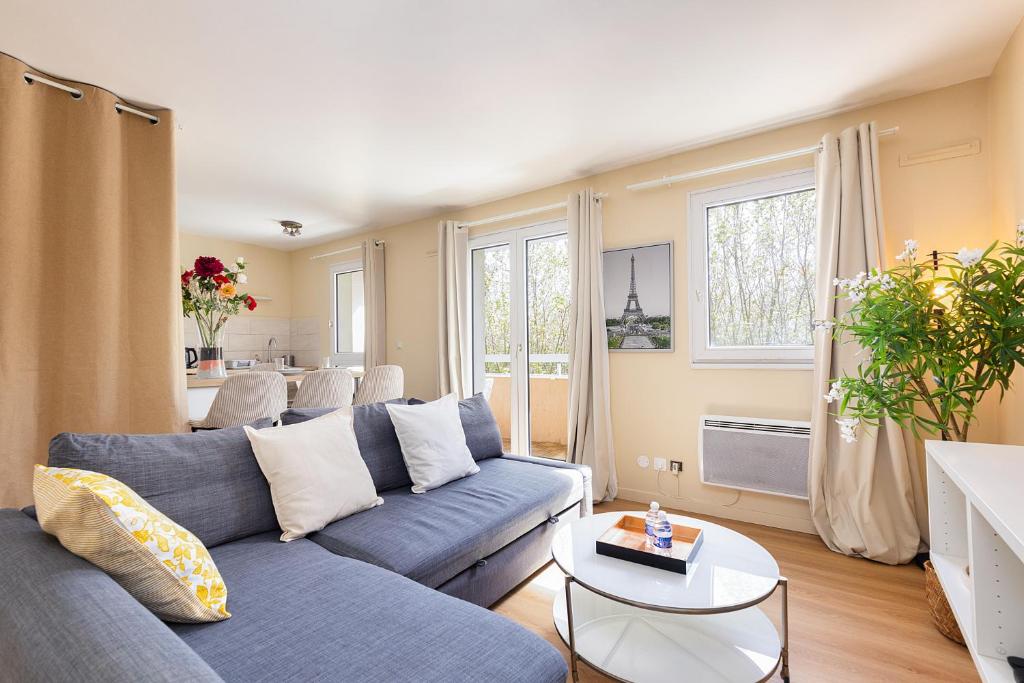 a living room with a blue couch and a table at Le Marnois-Gare in Noisy-le-Grand