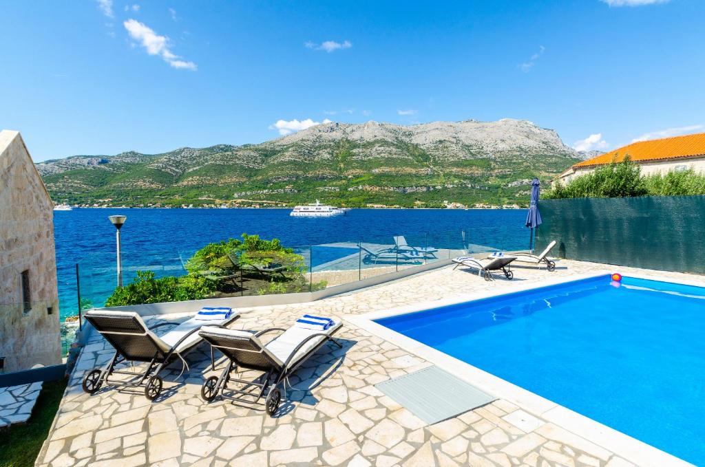 a swimming pool with chairs and a view of the water at Villa Gabriela in Korčula