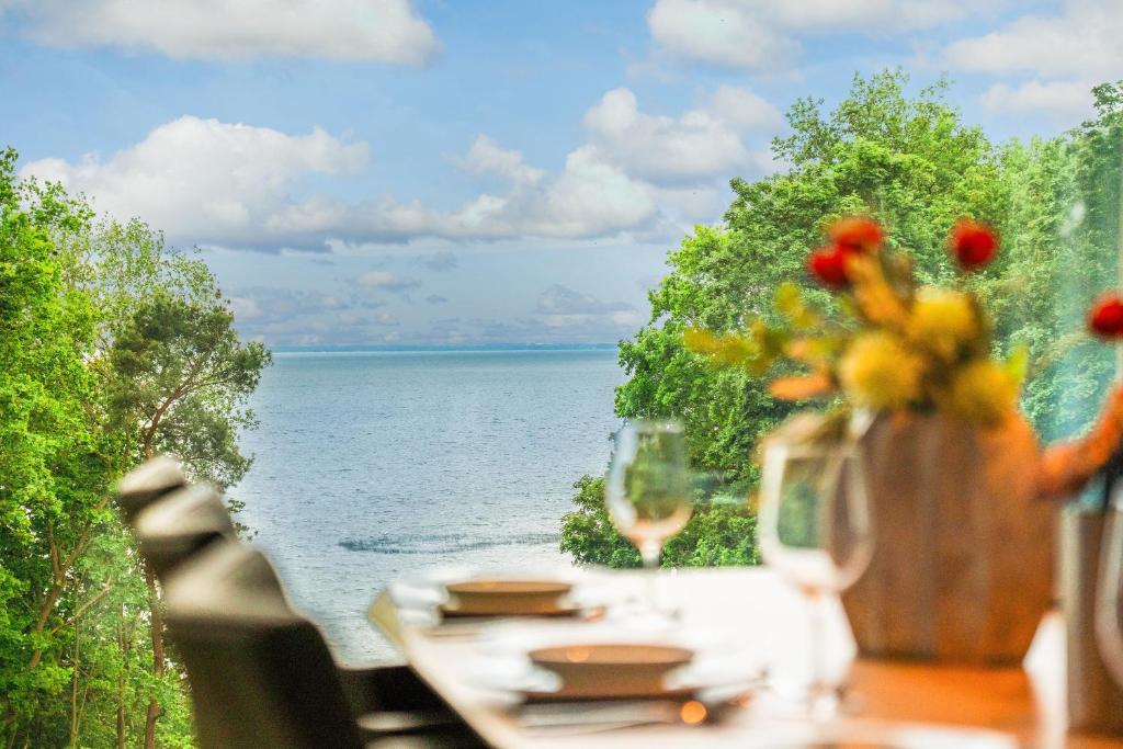 a table with a view of the water with flowers on it at Apartment "Liv" - DECK9 Am Haff in Garz