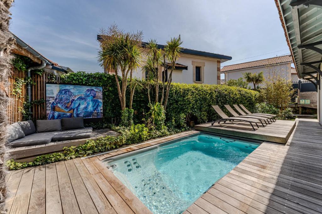 a backyard with a swimming pool and a wooden deck at La Villa Sanson in Arcachon